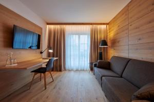 a living room with a couch and a desk at Sonne 1806 - Hotel am Campus Dornbirn in Dornbirn