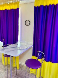 una mesa y sillas con cortinas moradas y amarillas en Квартира в центре (р-н Аян Пассаж), en Temirtaū