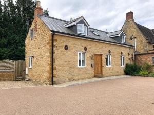 a brick house with a wooden door on a driveway at The Manor Barn in Northampton