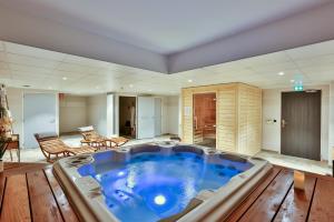 Habitación con bañera de hidromasaje grande y suelo de madera. en Hôtel & Spa FACE À LA MER, en Merville-Franceville-Plage