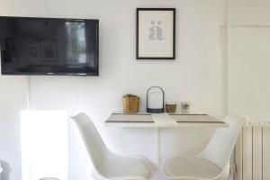 a white chair in a living room with a tv at NEW Renovated COZY APPARTMENT CENTRIC in Barcelona