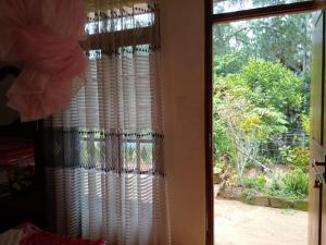 une porte menant à une chambre avec une fenêtre et des rideaux dans l'établissement Pleasure Mount Homestay, à Ella