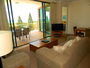 a living room with a couch and a table and a television at Santorini Twin Waters in Mudjimba