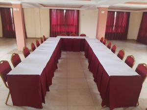 KILIMANI BREEZE HOTEL في Wote: طاولة طويلة في غرفة مع ستائر حمراء
