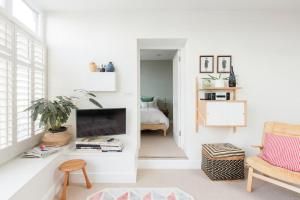 a living room with white walls and a tv at The Old Post Office Apartment in Falmouth