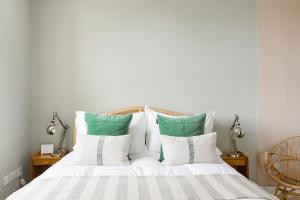 a bedroom with a bed with green and white pillows at The Old Post Office Apartment in Falmouth