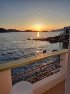 a sunset over the water from a balcony at Milos By The Sea - Eco House in Areti