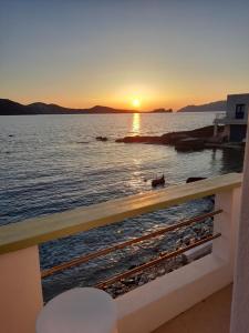 a sunset over the water from a balcony at Milos By The Sea - Eco House in Areti