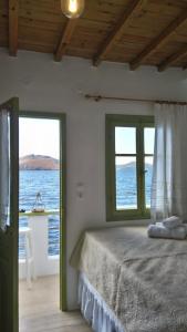 a bedroom with a bed and two windows with the ocean at Milos By The Sea - Eco House in Areti