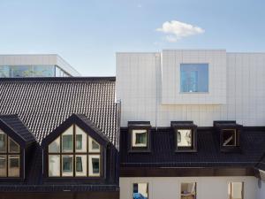 un edificio con techo negro y ventanas frente a un edificio en PM & Vänner Hotel en Växjö