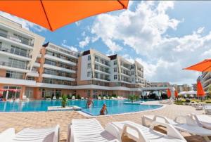 a hotel swimming pool with white chairs and umbrellas at Grand Kamelia Holiday Apartments in Sunny Beach