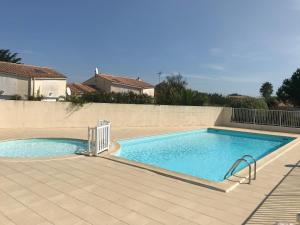 a large swimming pool on a tiled patio at À 150m de la plage in La Bétaudière