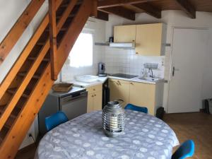 a kitchen with a table and blue chairs in a room at À 150m de la plage in La Bétaudière