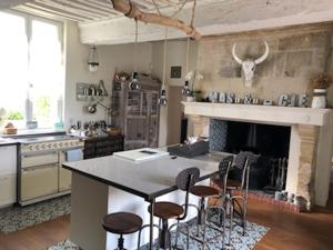 a kitchen with a counter with stools and a fireplace at Domaine "Les Bois Flottes" dans Maison de Charme au bord de mer et proche de Cabourg in Merville-Franceville-Plage