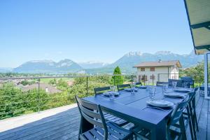 a blue table with chairs on a balcony with mountains at La Petite Montagne in Saint-Jorioz