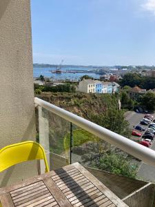 a balcony with a yellow chair and a view of a parking lot at 5 Porth Gwel in Falmouth