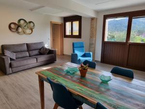 a living room with a wooden table and blue chairs at Apartamentos Ria de Aldan in Aldán