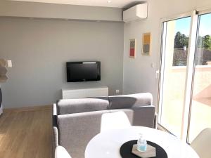 salon z kanapą i telewizorem na ścianie w obiekcie La Parenthèse Balnéo T2 Cosy de 40m² avec terrasse w mieście Ternay