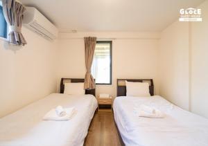 two twin beds in a room with a window at 石田ヴィレッジ 満天の星空が見えるログハウスを貸し切り 宮古空港から8分 無料駐車場付 長期滞在可 in Miyako Island