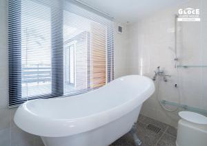 a white bath tub in a bathroom with a window at 石田ヴィレッジ 満天の星空が見えるログハウスを貸し切り 宮古空港から8分 無料駐車場付 長期滞在可 in Miyako Island