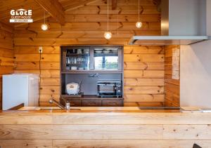 a kitchen with wooden walls and a refrigerator at 石田ヴィレッジ 満天の星空が見えるログハウスを貸し切り 宮古空港から8分 無料駐車場付 長期滞在可 in Miyako Island