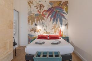 a bedroom with a bed with red pillows and a mural at Gabylou in Bordeaux