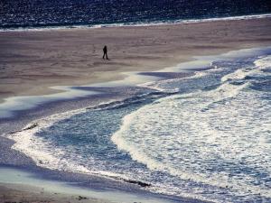 a person walking on a beach near the water at Easterhoull Chalets in Scalloway