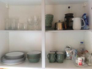Scalloway的住宿－Easterhoull Chalets，厨房里两个带盘子、杯子和盘子的架子