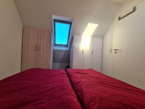 Schlafzimmer mit einem großen roten Bett und einem Fenster in der Unterkunft Ferienwohnung Rotmoosblick direkt am Rande unberührter Natur in Isny im Allgäu