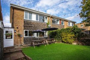 a house with two picnic tables and two umbrellas at Perfect for Contractors - Canterbury - Free parking - Ultra WiFi in Canterbury