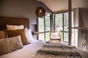 a bedroom with a bed and a chair and windows at The Edge Villa in Mount View