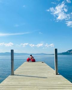 une personne assise sur un quai dans l'eau dans l'établissement Nice little house right by the sea, stunning view!, à Renså