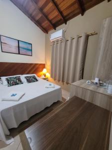 Un dormitorio con una cama y una mesa. en Mares de Camburizinho en Camburi