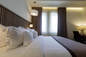 a large white bed in a hotel room with a window at D'avenue Boutique Hotel Accra in Accra