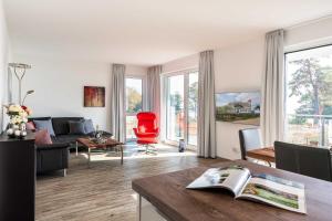 a living room with a couch and a red chair at Appartement "Seeadler" - Oase am Haff in Garz