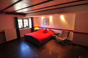 a bedroom with a red bed and a chair at SLEEP INN Appartement in Amblève
