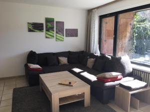 a living room with a black couch and a table at Ferienwohnung Waldblick in Todtnau