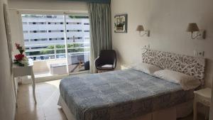 ein Schlafzimmer mit einem Bett, einem Fenster und einem Stuhl in der Unterkunft Hostal Roberto in Palmanova