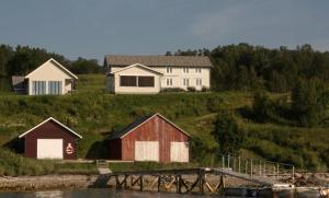 a house on a hill next to a body of water at Nice little house right by the sea, stunning view in Renså