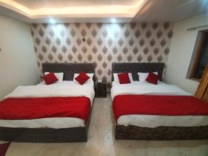 Baakhli Guest House and restaurant في Bhowāli: سريرين في غرفة مع وسائد حمراء