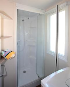 a white bathroom with a shower and a sink at Camping Miami plage in Poggio-Mezzana