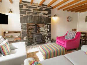 a living room with a stone fireplace and a pink chair at Pen y Cwm in Penmachno