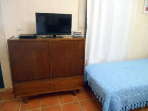 a bedroom with a tv on a dresser with a bed at Polytropon Studio ground floor in Kefallonia