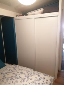 1 dormitorio con armarios blancos y 1 cama en Petite habitation meublée, en Biganos