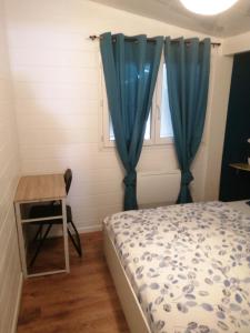 a bedroom with a bed and a table and a window at Petite habitation meublée in Biganos