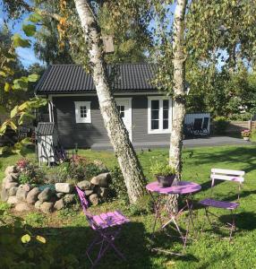 duas cadeiras roxas e uma mesa em frente a uma casa em VillaAttefall em Färjestaden