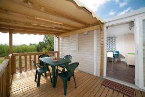 a patio with a table and chairs on a deck at Camping Miami plage in Poggio-Mezzana