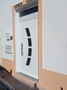 una puerta blanca con una señal en el lateral de un edificio en Casa das Bonecas en Vila Real de Santo António