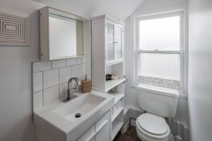 a white bathroom with a sink and a toilet at The Loft At Hiltz House in Halifax
