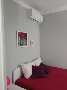 1 dormitorio con 1 cama con sábanas rojas y almohadas moradas en Casa das Bonecas en Vila Real de Santo António